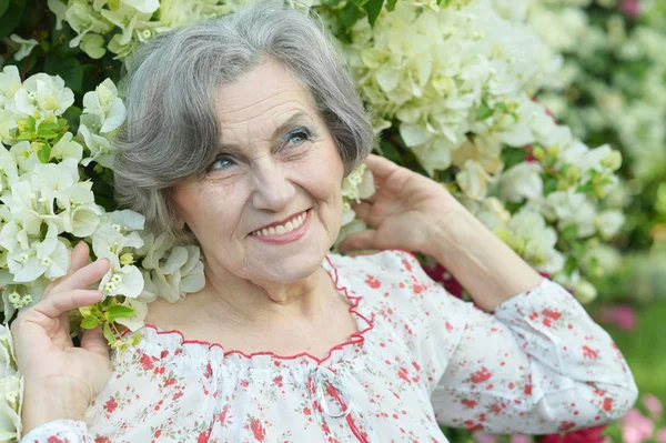 Older woman with white flowers — Stock Photo, Image