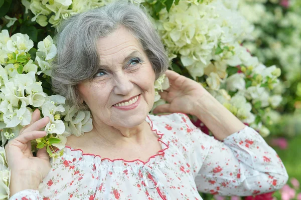 Äldre kvinna med vita blommor — Stockfoto