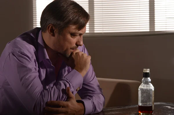 Sad young man drinks whiskey — Stock Photo, Image