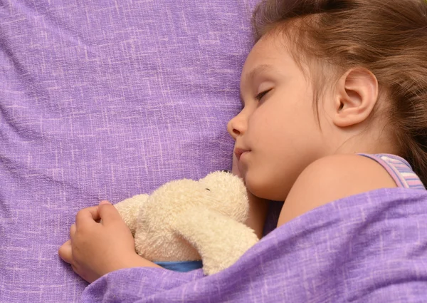 Klein meisje slaapt met speelgoed — Stockfoto