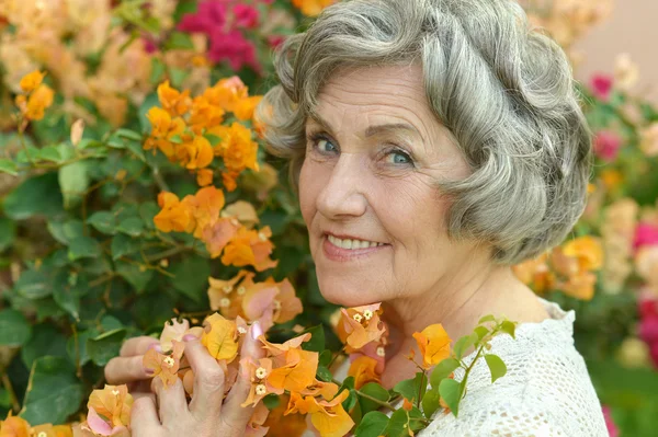 Idősebb nő, a sárga virágok — Stock Fotó