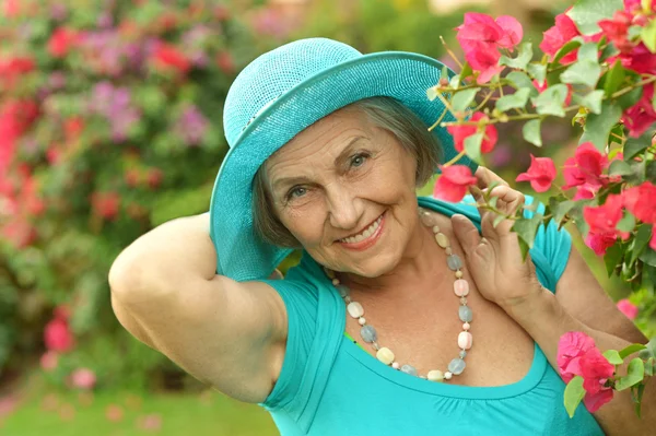 Starší žena na procházku s červenými květy — Stock fotografie