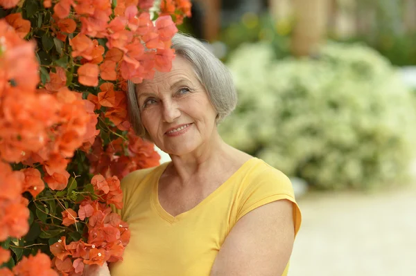 Äldre kvinna med gula blommor — Stockfoto