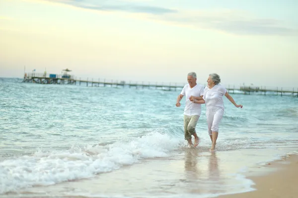 Old couple running on sea beach — Stock Photo, Image