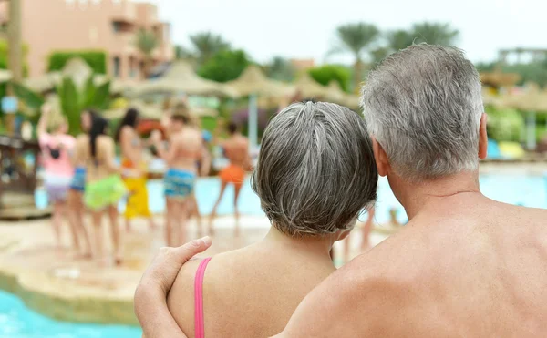 Pareja mayor de pie junto a la piscina — Foto de Stock