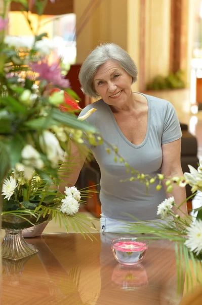 Äldre kvinna som står nära bordet — Stockfoto