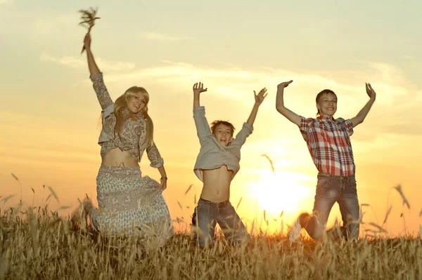 Familjen hoppa i fältet i kväll — Stockfoto