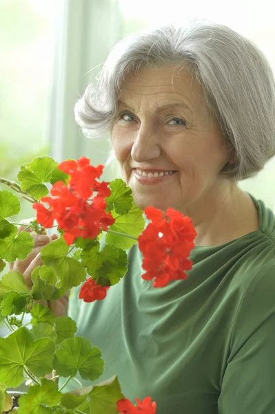 Äldre kvinna med röda blommor — Stockfoto