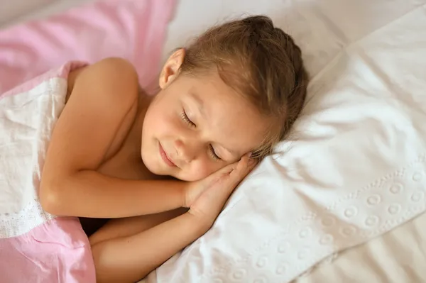 Roztomilá dívka spí v posteli — Stock fotografie
