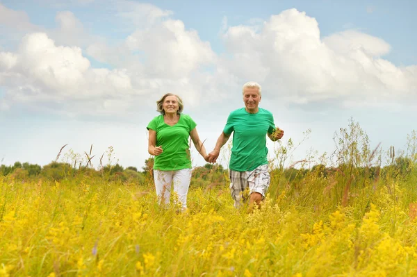 Senior couple running in summer field — Stock Photo, Image