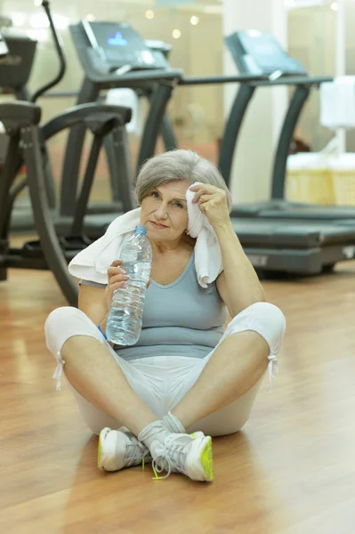 Старшая женщина питьевая вода в тренажерном зале — стоковое фото