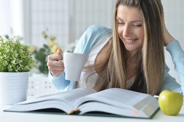 Genç Bir Kadın Kitap Okuyor Evde Kahve Içiyor — Stok fotoğraf