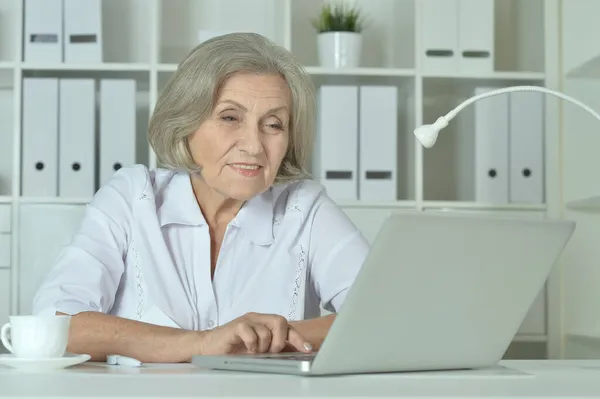 キャビネットでノートパソコンを操作している先輩女性医師が — ストック写真