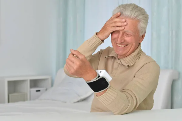 Starszy Mężczyzna Stosujący Automatyczny Tonometr Nadgarstka Szpitalu — Zdjęcie stockowe