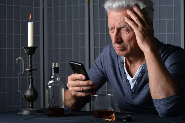 Kavkazský Starší Muž Smartphonem Láhev Alkoholu Stole — Stock fotografie