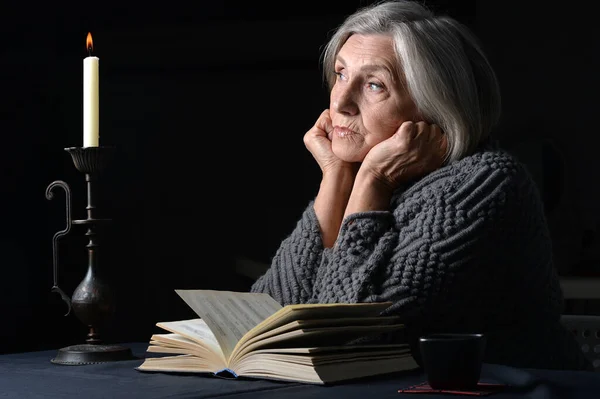 Senior Vrouw Met Boek Thuis Een Donkere Achtergrond — Stockfoto
