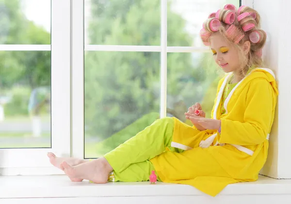 Beautiful little girl with nail polish by window