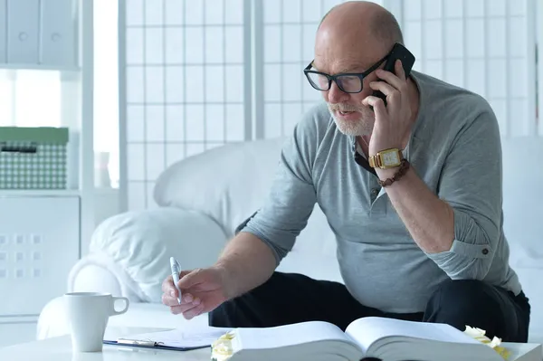 Senior Man Met Boek Praten Telefoon Het Maken Van Aantekeningen — Stockfoto