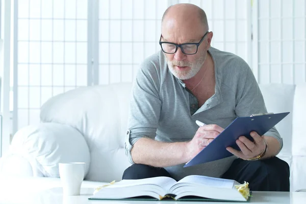 Senior Man Met Boek Aan Het Werk Thuis — Stockfoto