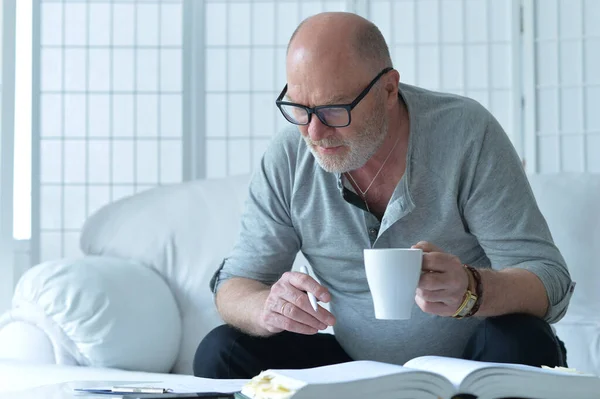 Senior Man Met Boek Aan Het Werk Thuis — Stockfoto