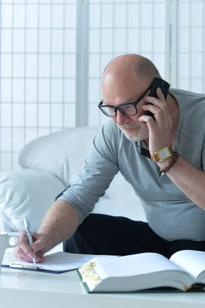 Senior Man Met Boek Praten Telefoon Het Maken Van Aantekeningen — Stockfoto