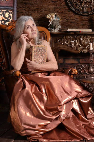 本を持つ椅子の上の美しい先輩女性 — ストック写真