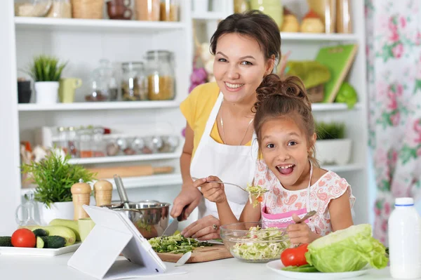 可愛いです女の子とともに彼女のお母さん料理とともにキッチンテーブル — ストック写真
