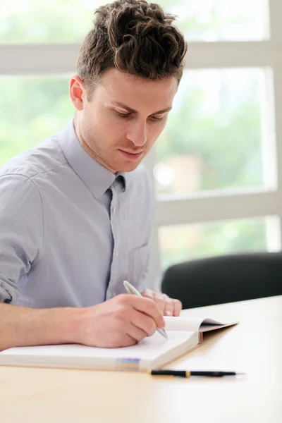 Jovem adulto homem escrevendo nota — Fotografia de Stock