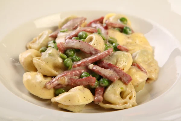 Tortellini com presunto e ervilhas Fotografia De Stock