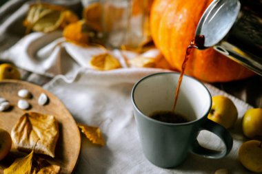 Mutfak masasında bir balkabağı ve sonbahar yaprakları var.