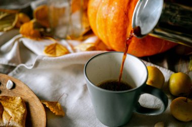 Mutfak masasında bir balkabağı ve sonbahar yaprakları var.