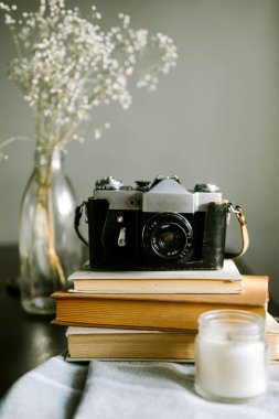 Eski Sovyet fotoğraf makinesi kitaplar, vazo dolusu kuru çiçekler ve arka planda mum, yakın görüş. 