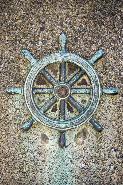 Ships steering wheel decoration on concrete wall — Stock Photo, Image