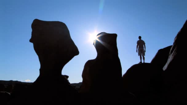 Hombre sobre roca en silueta — Vídeo de stock