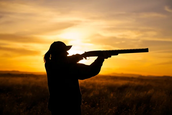 Vrouw hooggelegen spel jager in zonsondergang — Stockfoto
