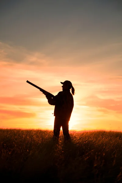 Kvinna höglänta spelet jägare i solnedgången — Stockfoto