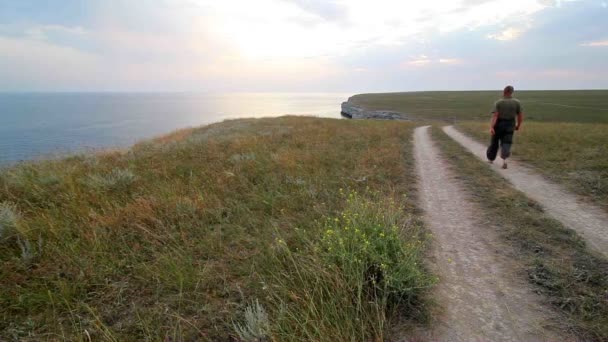 Mannen går barfota på road nära havet — Stockvideo