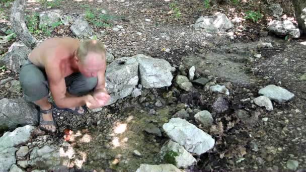 Человек пьет воду из ручья — стоковое видео