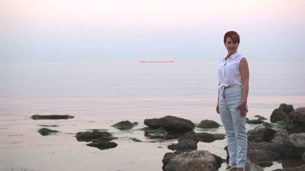 Гармоничная милая женщина стоит на берегу моря и улыбается — стоковое видео