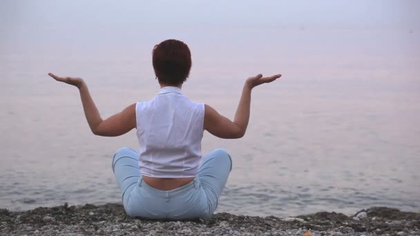 A meditáló nő, a tenger partján — Stock videók