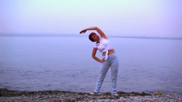 The harmonous woman does exercises on the seashore — Stock Video
