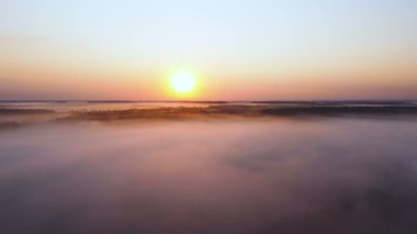 Bulutların üzerinde güzel bir yan uçuş, gündoğumunda kızıl güneşli bir tahta. Hava manzarası