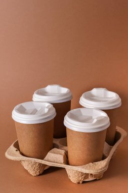 Paket kahve için bardak tutacağında kağıt bardaklar. Kağıt bardak ve bir içki. Tek kullanımlık sofra takımı. Eko karton geri dönüşümlü. Kahverengi arka plan. Boşluğu kopyala