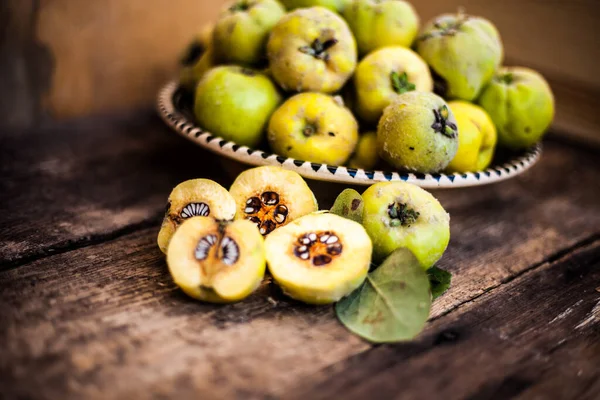 Quince fruits on a wooden background. Harvest of autumn fruits. Yellow tart hard fruit. Cut apple-quince with leaf. Terry grade. Healthy vitamin food. — Stock Photo, Image