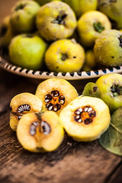 Quince fruits on a wooden background. Harvest of autumn fruits. Yellow tart hard fruit. Cut apple-quince with leaf. Terry grade. Healthy vitamin food.