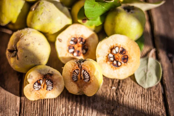 Quince fruits on a wooden background. Harvest of autumn fruits. Yellow tart hard fruit. Cut apple-quince with leaf. Terry grade. Healthy vitamin food. — Stock Photo, Image