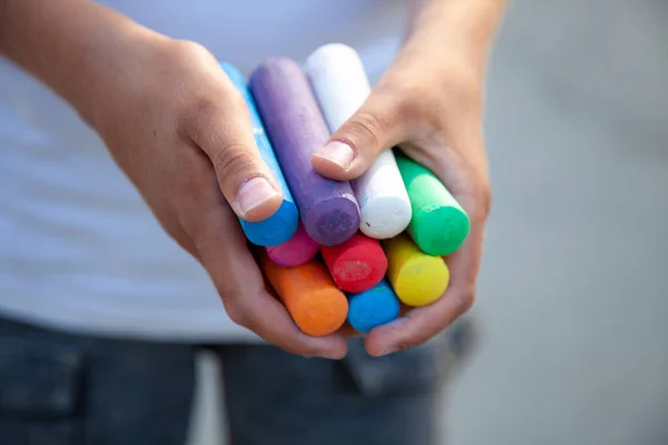 Chalks. Large multi-colored crayons in childrens hands. The child holds the chalk. Draw on the street. Fascinating drawing for children — Stock Photo, Image