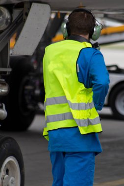 Yansıtıcı yelek giyen bir adam. Teknisyen türbinde oturur ve uçmadan önce uçak motorlarını kontrol eder. Havacılık bakımı, onarım. Havaalanı çalışanı. Güvenlik kontrolü. Uçak motorunun arızaları.