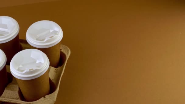 테이크 웨이 커피 를 담기 위해 컵에 종이 컵 을 담는다. 종이컵에 술 한잔. 처리 가능 한 식탁용 식기. 에코 마분지 재활용 가능. 갈색 배경. 복사 공간 — 비디오