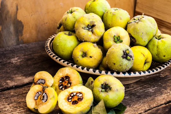 Quince fruits on a wooden background. Harvest of autumn fruits. Yellow tart hard fruit. Cut quince with leaf. Terry grade. Healthy vitamin food.